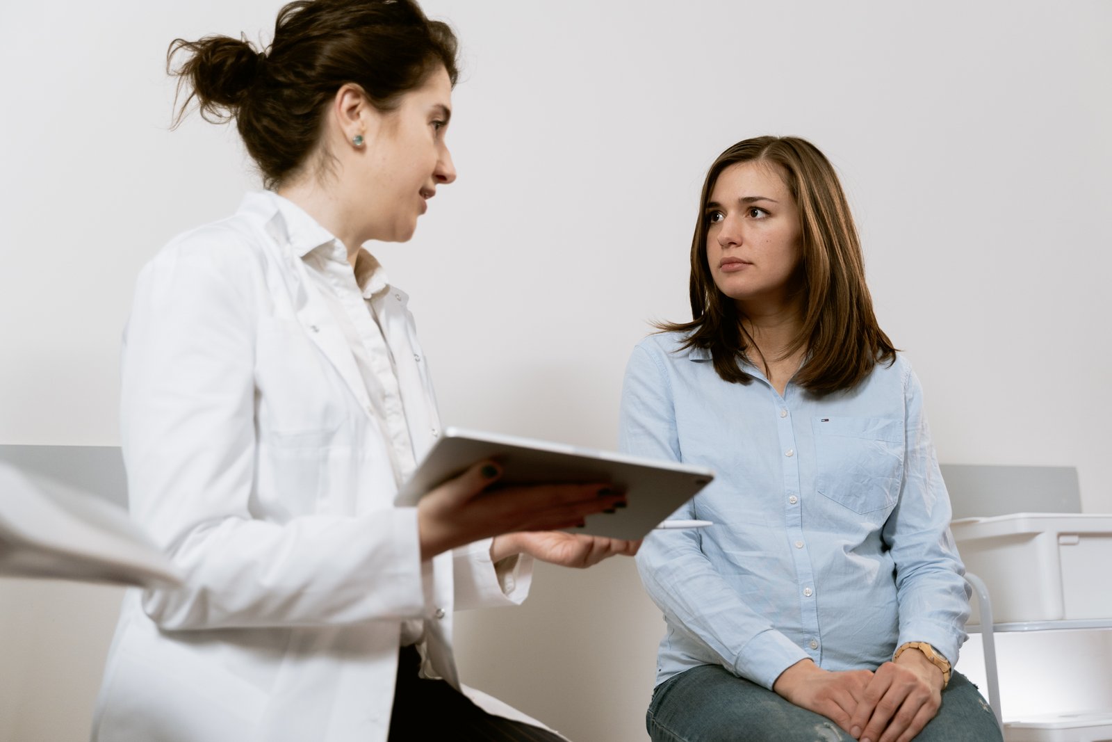 En kvinna sitter hos gynekologen och pratar med henne.