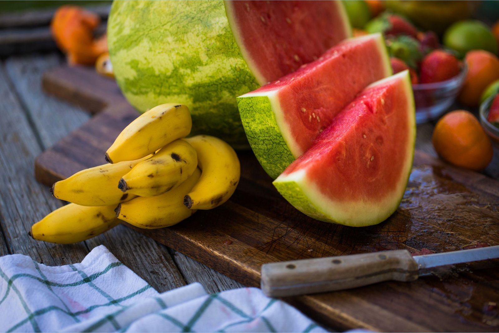 Kaliumrika bananer ligger bredvid en L-citrullinrik skivad vattenmelon på en skärbräda.