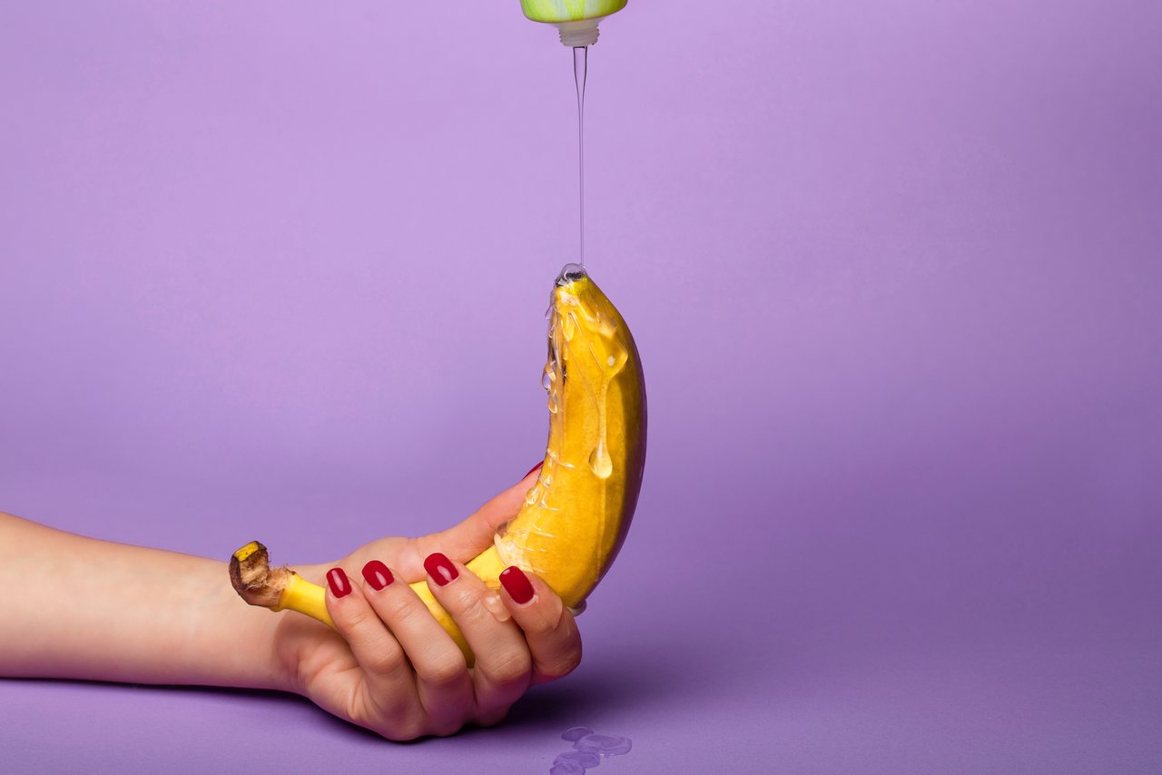 Smörjmedel körs över en banan som hålls med en hand.
